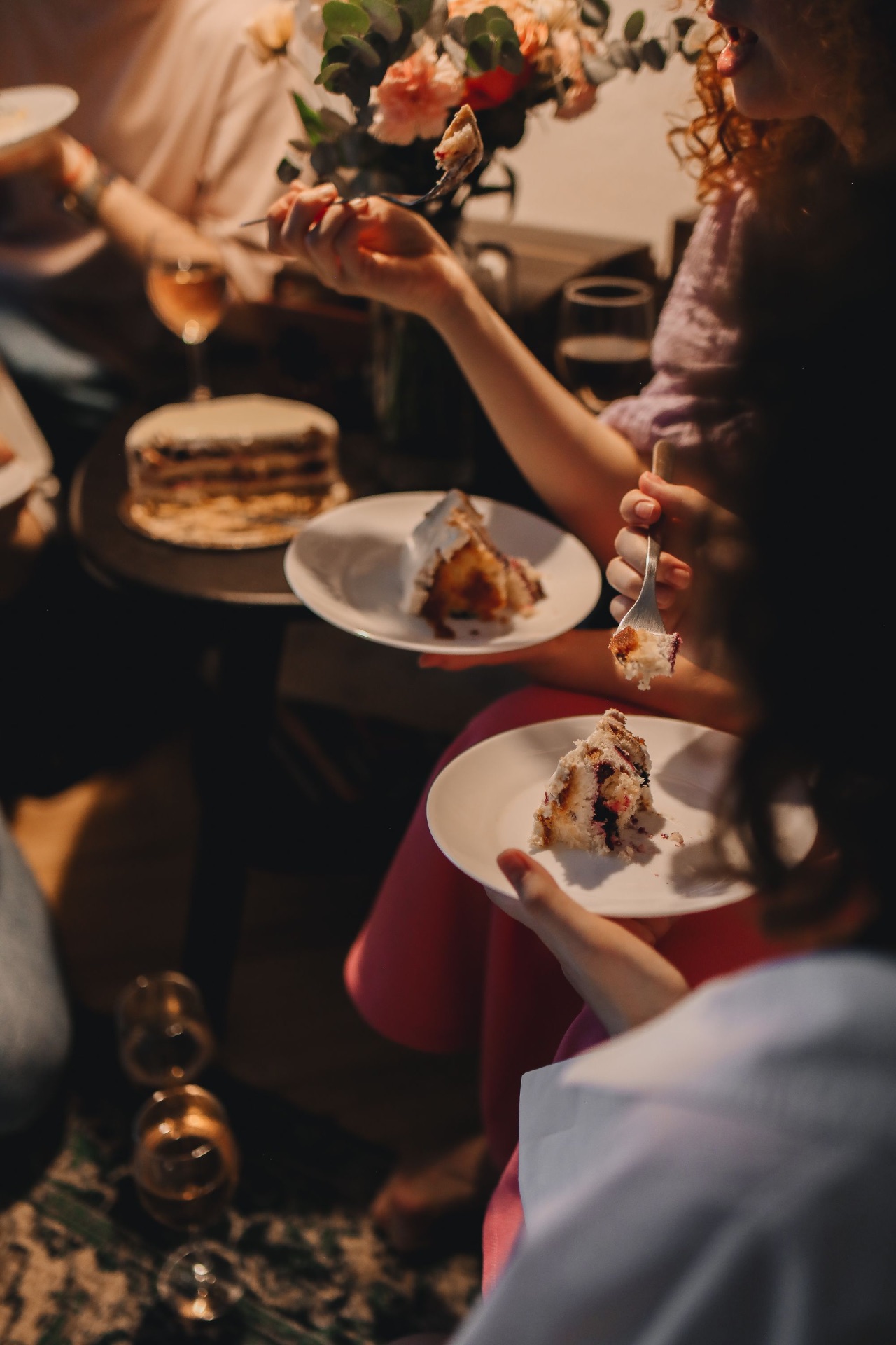 Women sharing slices of cake by candlelight