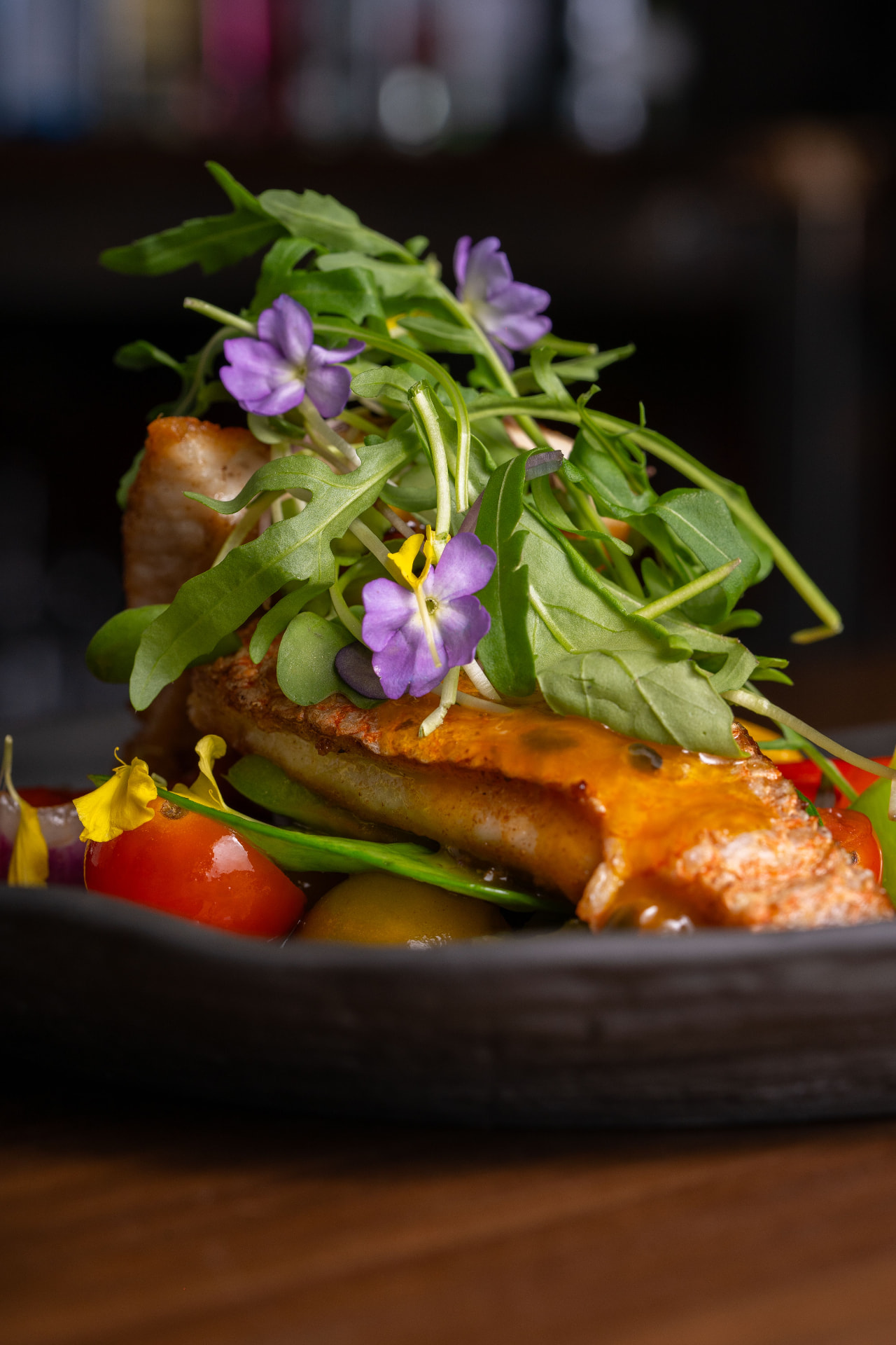 Glazed salmon with arugula, edible flowers, and roasted vegetables
